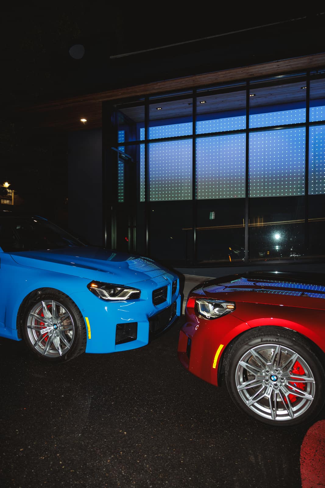 Red and blue nose to nose in front of a lit LED facade