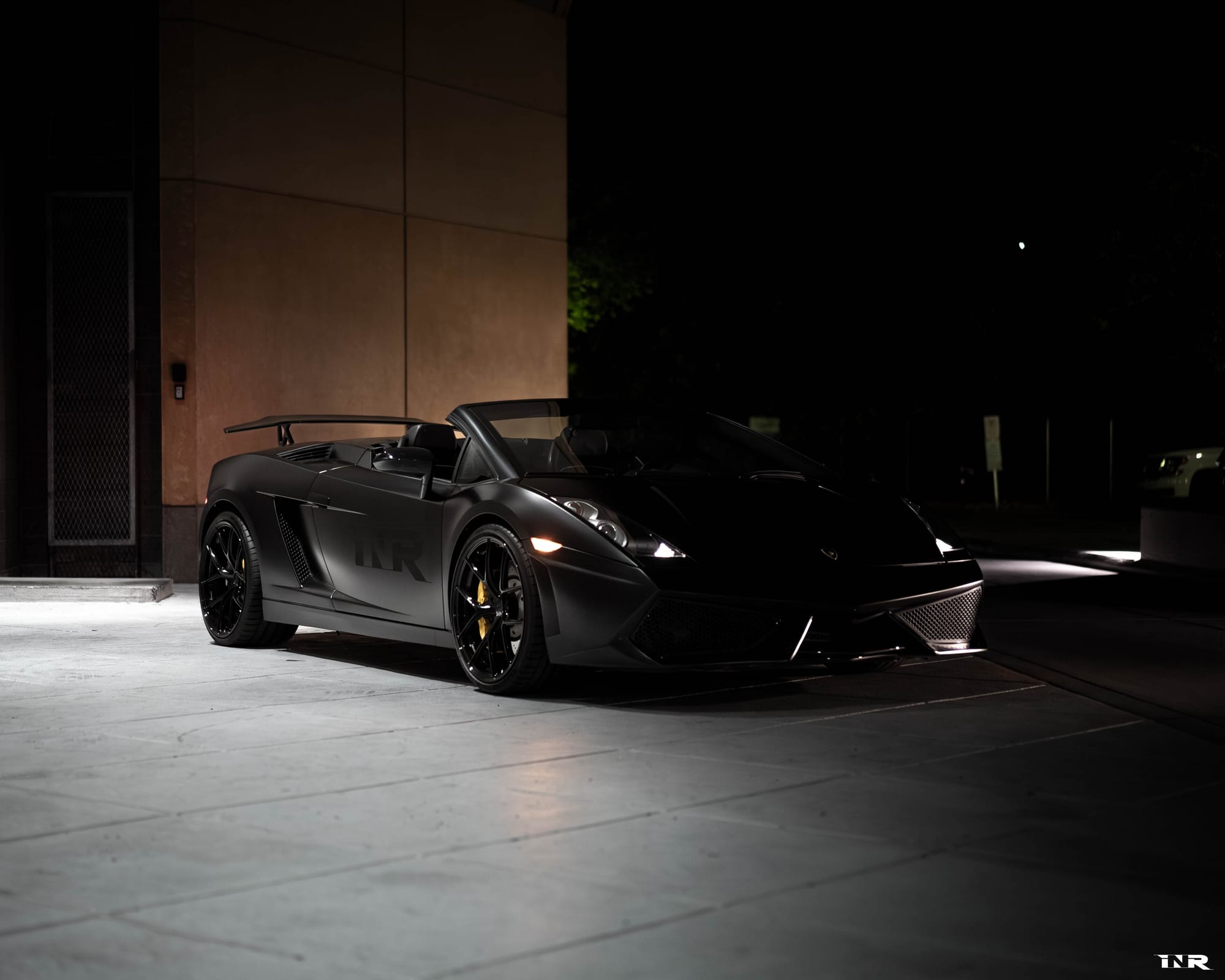 Front three-quarter at night, parked against a lit wall
