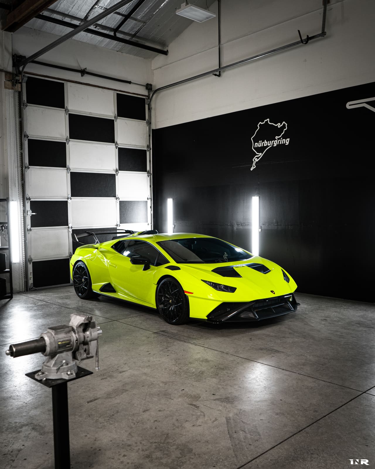 Green STO parked in the shop bay under the Nürburgring sign